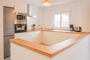 a kitchen with white cabinets and a stainless steel refrigerator at Tarifa Cozy House - Casita Central in Tarifa