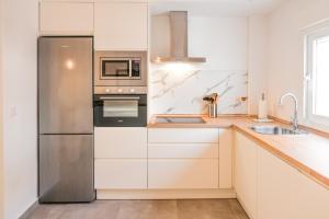 a kitchen with white cabinets and a stainless steel refrigerator at Tarifa Cozy House - Casita Central in Tarifa