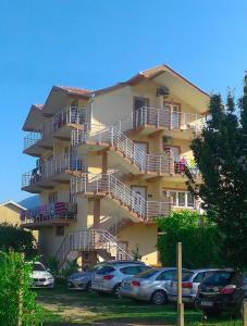 un gran edificio amarillo con coches estacionados frente a él en Apartments Nedovic-Jaz en Budva