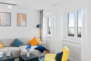 un soggiorno con un divano e due finestre di Anytime - Ferienwohnungen am Uferpark direkt am See a Friedrichshafen