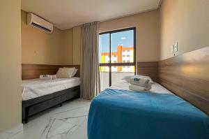 a hotel room with two beds and a window at Bessa Apto Novinho 200m Praia 2 Quartos 5 Pessoas in Nossa Senhora do Livramento +17 photos