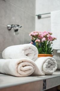 einen Haufen Handtücher auf der Badezimmertheke mit einer Blumenvase in der Unterkunft Apart del Bosque La Cumbrecita in La Cumbrecita