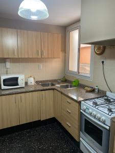 eine Küche mit Mikrowelle und Herd oberen Backofen in der Unterkunft Departamento Pleno Centro Amplio y Cómodo in San Salvador de Jujuy