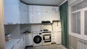 a kitchen with white cabinets and a washing machine at Апартамент Азия in Bishkek +1 photo