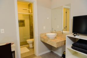 bagno con lavandino, servizi igienici e TV di Pousada Divino Oleiro - Gov. Celso Ramos a Governador Celso Ramos Altre 50 foto