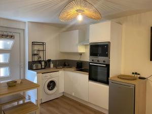 een keuken met witte kasten en een wasmachine en droger bij Le Suchet in Lyon