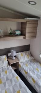 RhuddlanにあるSun Valley Caravan Park Rhuddlan RHYLのベッドルーム1室(ベッド2台、ランプ付きテーブル付) +9枚の写真