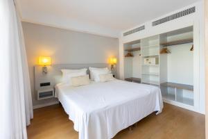 1 dormitorio blanco con 1 cama blanca y 2 almohadas en Hipotels Apartamentos Cala Bona, en Cala Bona 17 fotos más