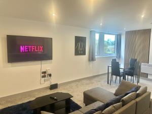 a living room with a couch and a tv on the wall at Two Bedroom Flat by Brookland Stays Serviced Accommodation Short Lets Leeds with Free WiFi in Leeds