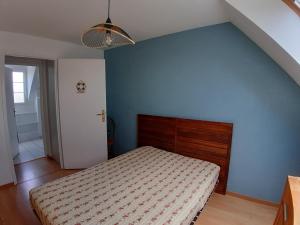 une chambre avec un lit et un mur bleu dans l'établissement Opal'In, au Crotoy