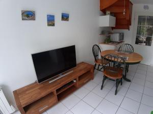 Il comprend un salon doté d'une télévision et d'une table avec des chaises. dans l'établissement Opal'In, au Crotoy
