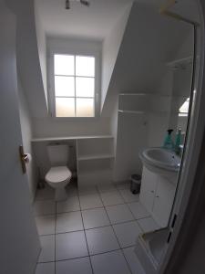 une salle de bain avec toilettes, lavabo et fenêtre dans l'établissement Opal'In, au Crotoy