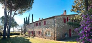 a large stone building with red shutters on it at La Casa Rossa in Marina di Bibbona