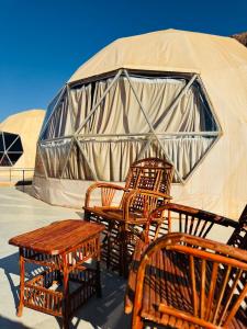 un groupe de chaises et de tables devant une tente dans l'établissement Rum Goldeneye luxury camp, à Wadi Rum