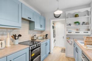 a kitchen with blue cabinets and a sink at Bay Tree Cottage - Cozy Norfolk Retreat in Heacham in Heacham