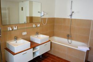 a bathroom with two sinks and a shower and a tub at Hotel Schlee in Hohenschäftlarn +37 photos