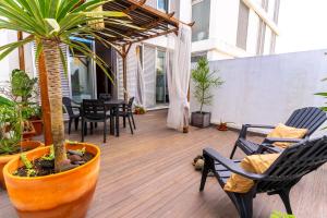 a patio with chairs and a table and a palm tree at epicenter CITY in Ponta Delgada