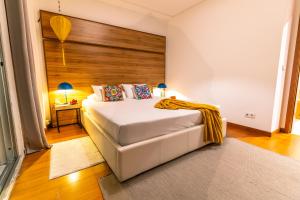 a bedroom with a white bed with a wooden headboard at epicenter CITY in Ponta Delgada