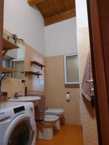 Un baño con lavadora y un inodoro. en Elvira, en Marina di Montenero
