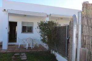 a white house with a patio with chairs and a fence at DADA CAÑOS in Los Caños de Meca