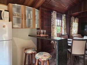 a kitchen with a counter with stools and a refrigerator at Cabana Family - Na Mata Atlântica in Juquitiba