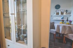 a glass cabinet with dishes in it next to a table at Violet Seaview Apartment in Vis