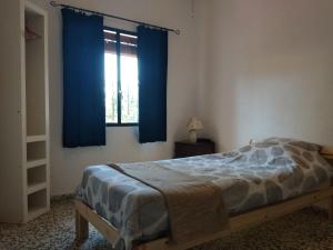 a bedroom with a bed and a window with blue curtains at Cottage in Alcuéscar +10 photos