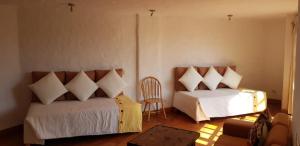 a bedroom with two beds and a chair at Hotel Rustica Lunahuana in Uchupampa
