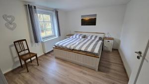 a bedroom with a bed and a chair and a window at Ferienwohnung Streckhofidylle in Osterode