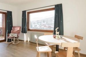 a dining room with a table and a large window at Appartamenti Terme Viola in Pozza di Fassa