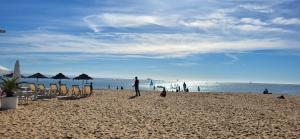 eine Person, die am Strand mit Stühlen und Sonnenschirmen steht in der Unterkunft Blue Rossio Studio in Lissabon + 4 Fotos