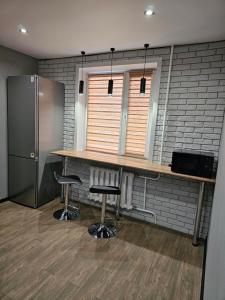 a kitchen with a table and two stools and a refrigerator at Квартира in Pavlodar