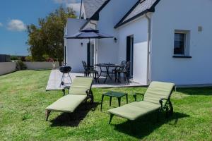 a patio with a table and chairs and an umbrella at Villa DUXCAAR in Saint-Pabu