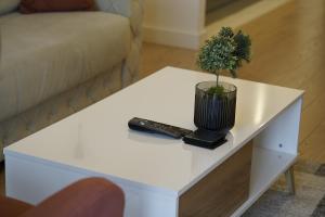 a white coffee table with a plant and a remote control at Best Apartments-Aqua-Belgrade Waterfront in Belgrade