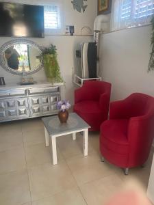 een woonkamer met 2 rode stoelen en een tafel bij El Palmeral in Playa Blanca