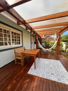 a porch with a hammock and a bench on a deck at Casa aconchegante em Garopaba in Garopaba