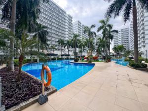 a swimming pool with palm trees and a large building at Shell Residences Pasay 1BR Walk to MOA Newly Renovated! in Manila
