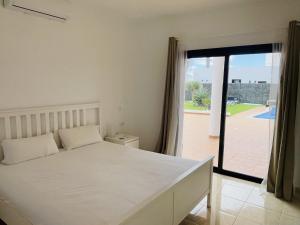 Un dormitorio con una cama blanca y una puerta corrediza de vidrio. en Villa Maria, en Playa Blanca 16 fotos más