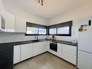 una cocina blanca con armarios blancos y ventanas en Villa Maria, en Playa Blanca