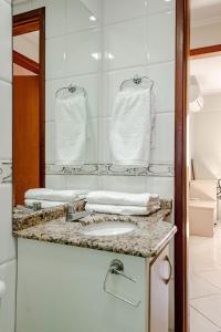 a bathroom with a sink and a mirror and towels at Ótimo apartamento, em excelente localização JL Shopping in Cascavel