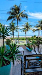 Apartamento Sol Nascente في برايا جراندي: اطلالة على شاطئ فيه نخل ومقعد