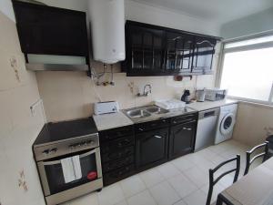a kitchen with black cabinets and a sink and a dishwasher at Lisbon spacious T2 in Damaia, Lisbon in Amadora