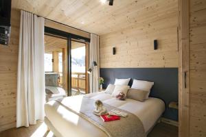 a bedroom with a large white bed in a room with wooden walls at Odalys Chalet L'Ours Brun in Les Deux Alpes