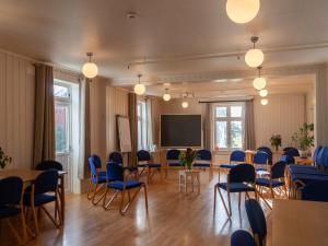 a meeting room with tables and chairs and a screen at Fokhol Gård Gjestehus in Stange