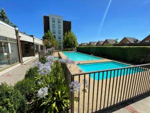 a swimming pool with a fence and purple flowers at Extraordinario depto ejecutivo in Los Ángeles