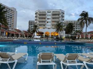 ein großer Pool mit Stühlen und Gebäuden in der Unterkunft Ixtapa zihuatanejo, Departamento vacacional- in Zihuatanejo