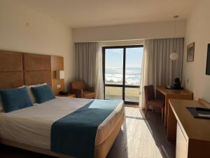 a hotel room with a bed and a view of the ocean at Hotel Atlantida Sol in Figueira da Foz +61 photos