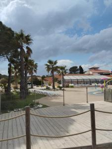a rope fence with palm trees and a building at Entre mer et montagne in Canet-en-Roussillon