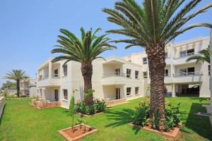 un gran edificio blanco con palmeras delante en Euronapa Hotel Apartments, en Ayia Napa