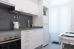 a white kitchen with white cabinets and a sink at Riversuites Apartments in Coimbra
